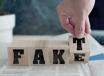 Vier Holzwürfel mit Buchstaben bilden ein Wort. Eine Hand bewegt den letzten Würfel, so dass man "Fake" oder "Fakt" lesen kann.