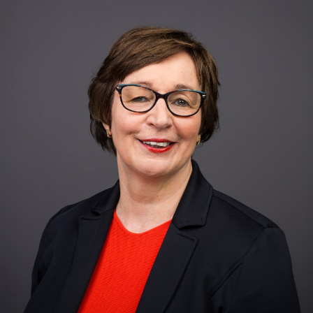 Porträtfoto von Astrid Funken, freundlich lächelnd, mit neutralem Hintergrund.