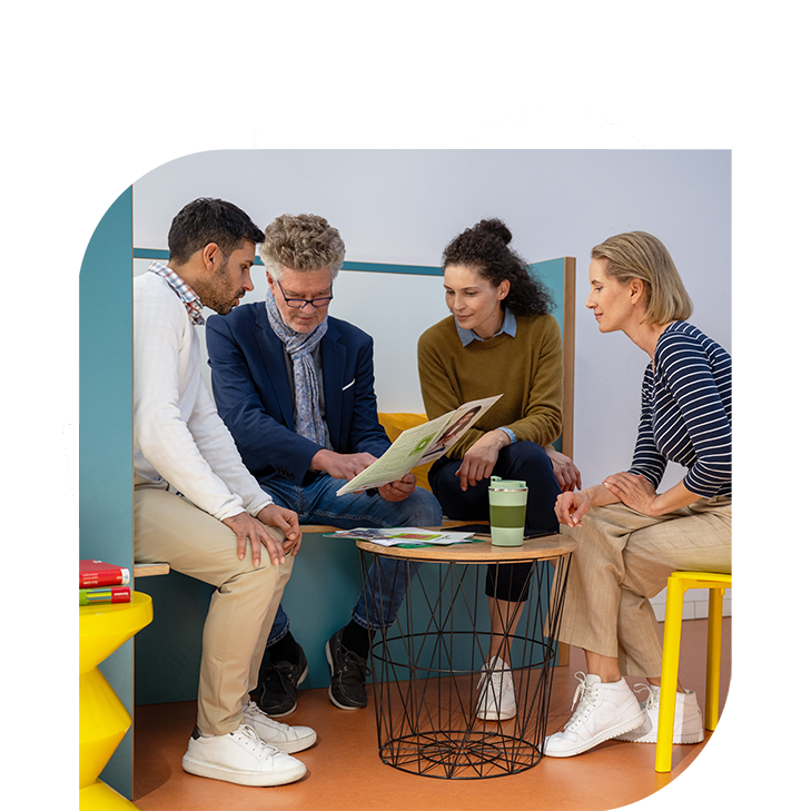 Vier Personen sitzen zusammen und sehen eine Broschüre an