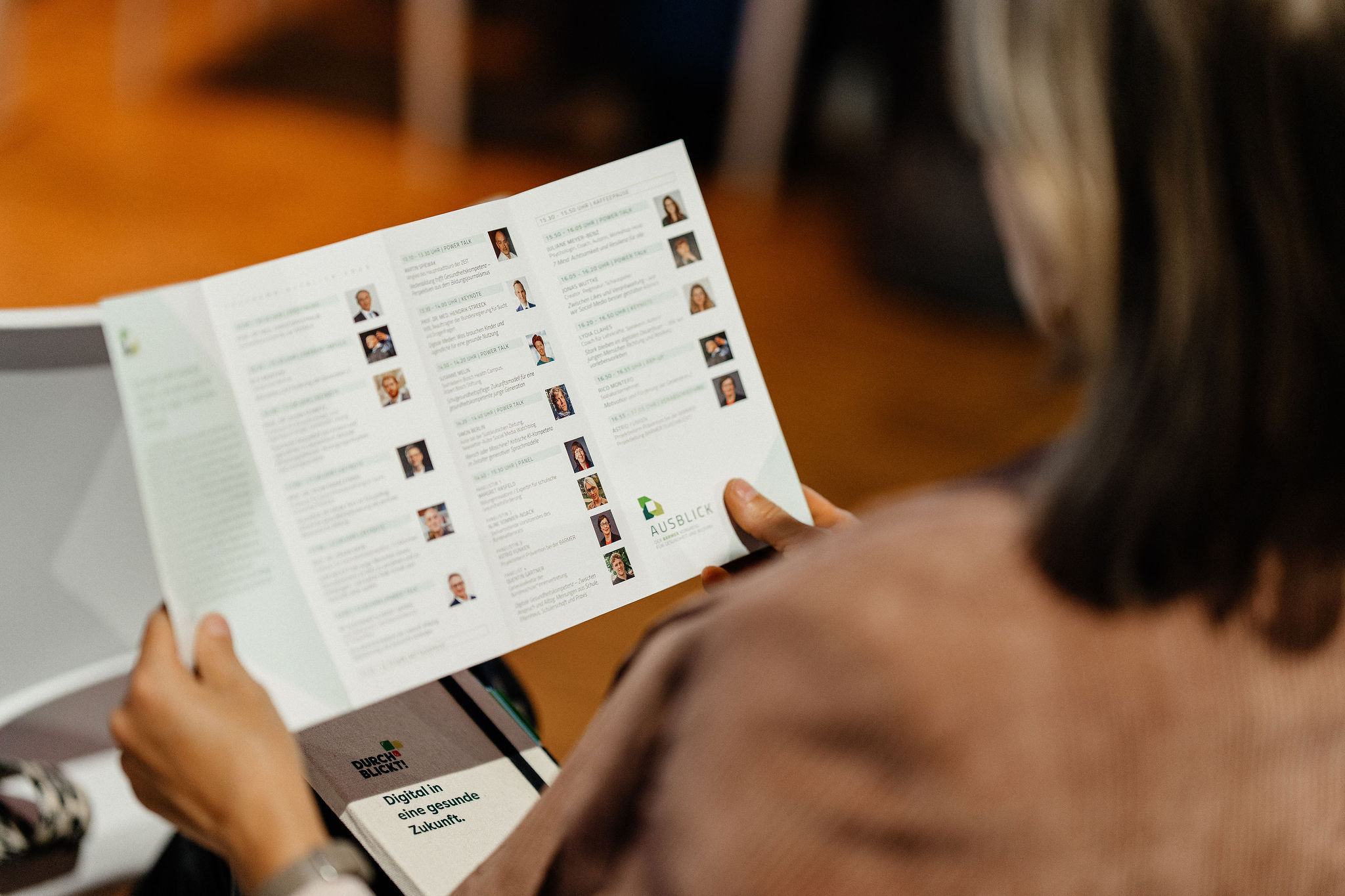 Eine Person hält das Programmheft des Barmer-Kongresses „Ausblick“ in den Händen und liest die Übersicht der Referentinnen und Referenten.